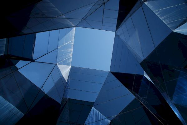 Geometric architecture with reflective glass panels creates a visually striking pattern against the blue sky above.