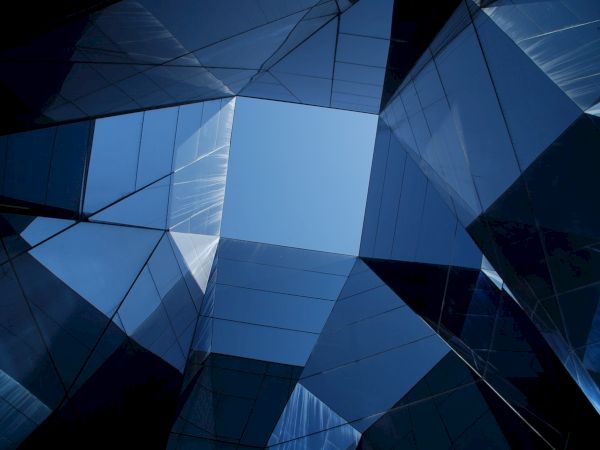 Geometric architecture with reflective glass panels creates a visually striking pattern against the blue sky above.