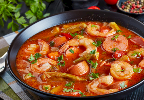 A hearty shrimp stew with sausage, tomatoes, peppers, potatoes, and herbs in a rich, tomatoy broth. Top it at 140 characters, always ending the sentence.