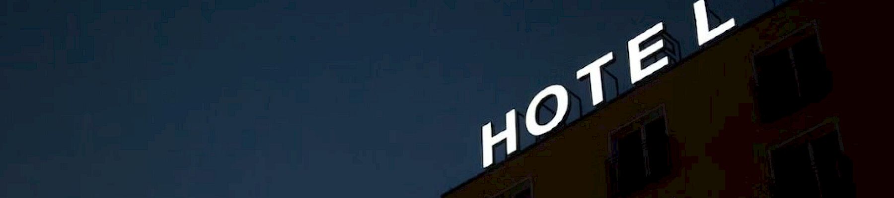 A building at night with the word "HOTEL" illuminated on the facade against a dark sky.