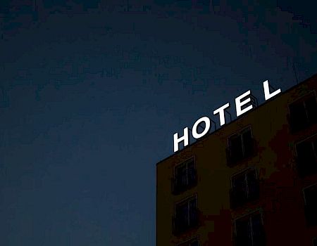 A building at night with the word "HOTEL" illuminated on the facade against a dark sky.