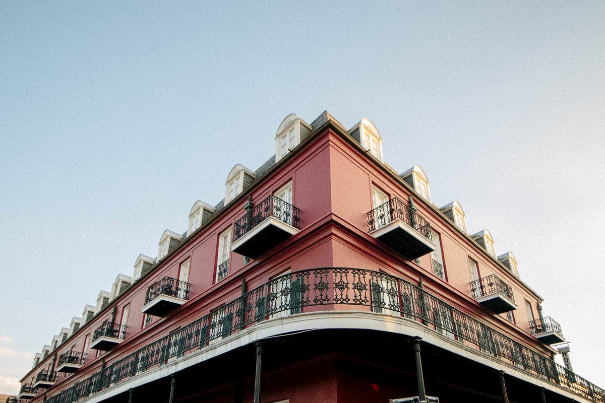 A red building with balconies and a balustrade under a clear sky