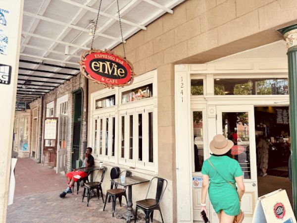 A street view shows the exterior of a café named "envie," with people sitting outside on a brick sidewalk.