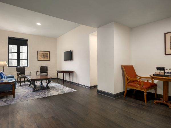 A modern living space with a couch, chairs, tables, and wall art, featuring a cozy seating area and a TV on the wall.
