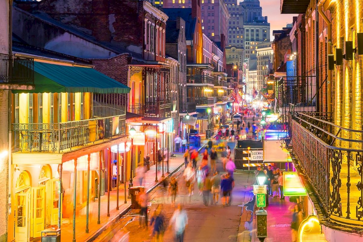 A vibrant street scene at night with people walking and buildings lit up.