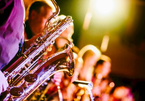 A group of musicians playing saxophones on stage, with warm lighting creating a vibrant and energetic atmosphere.