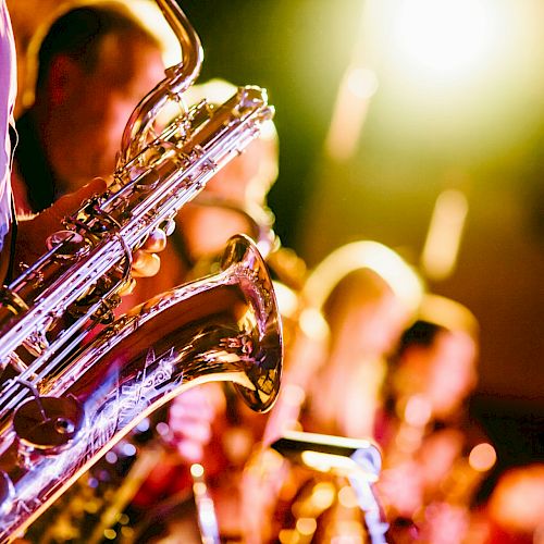 A group of musicians playing saxophones on stage, with warm lighting creating a vibrant and energetic atmosphere.