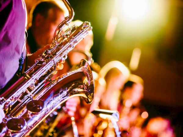 A group of musicians playing saxophones, captured under vibrant stage lighting, creates a lively and warm atmosphere.
