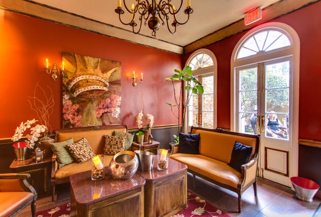A luxurious lounge with red walls, yellow couches, and a chandelier.