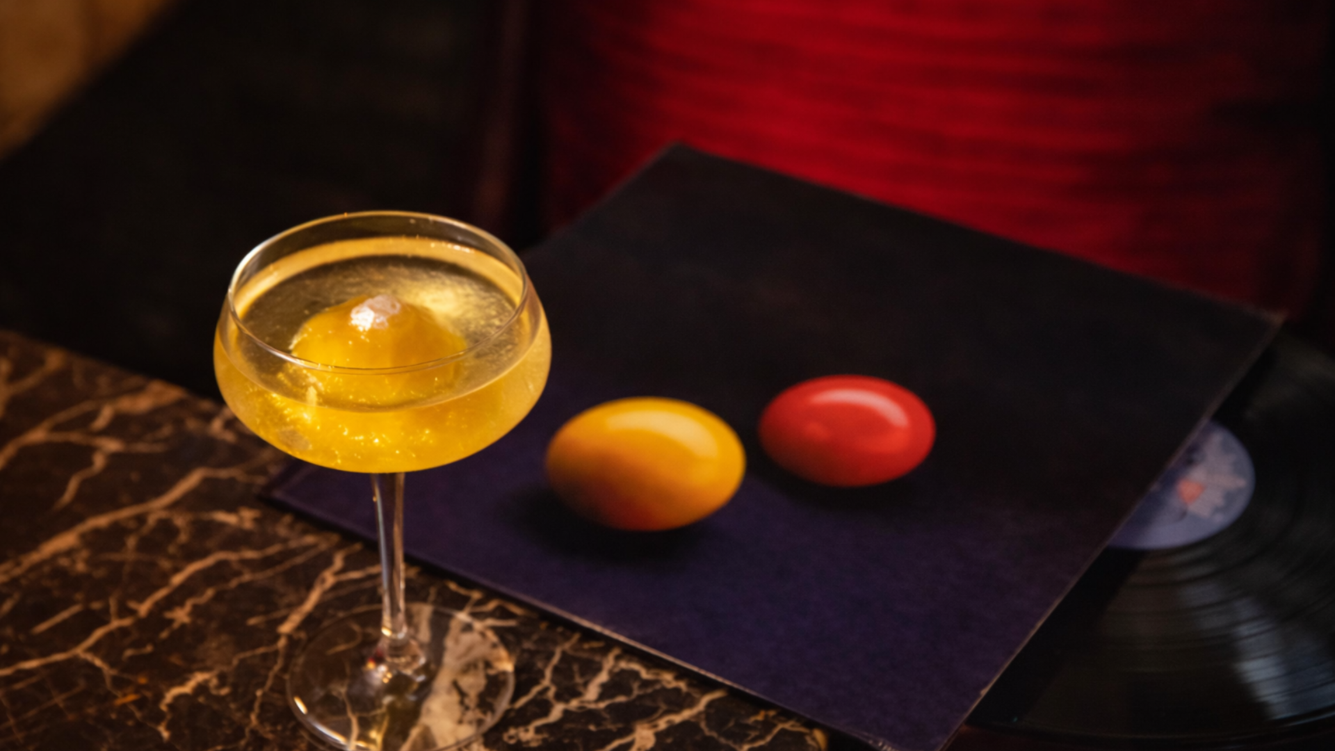 a cocktail on a table with a vinyl record