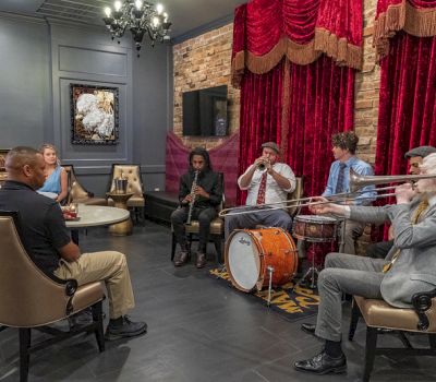 a group of people sitting in a lounge with musicians playing instruments