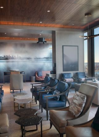 A modern lounge with comfortable seating, large windows offering a scenic water view, and artwork on the wall.