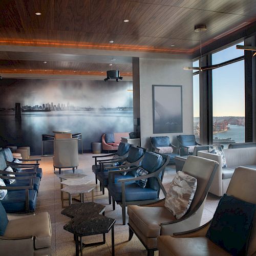 A modern lounge with comfortable seating, large windows offering a scenic view, and stylish lighting, creating a cozy atmosphere.